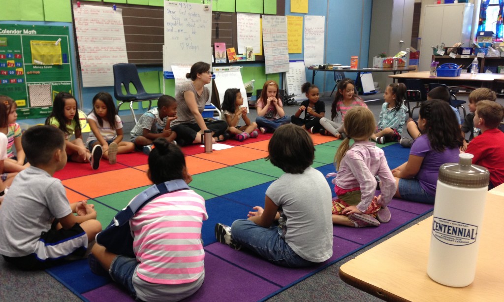 Classroom of students sitting on the floor with the teacher