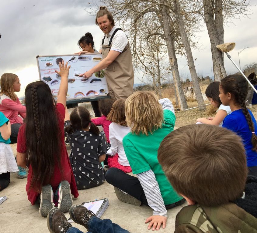 Student raising hand in science class outside